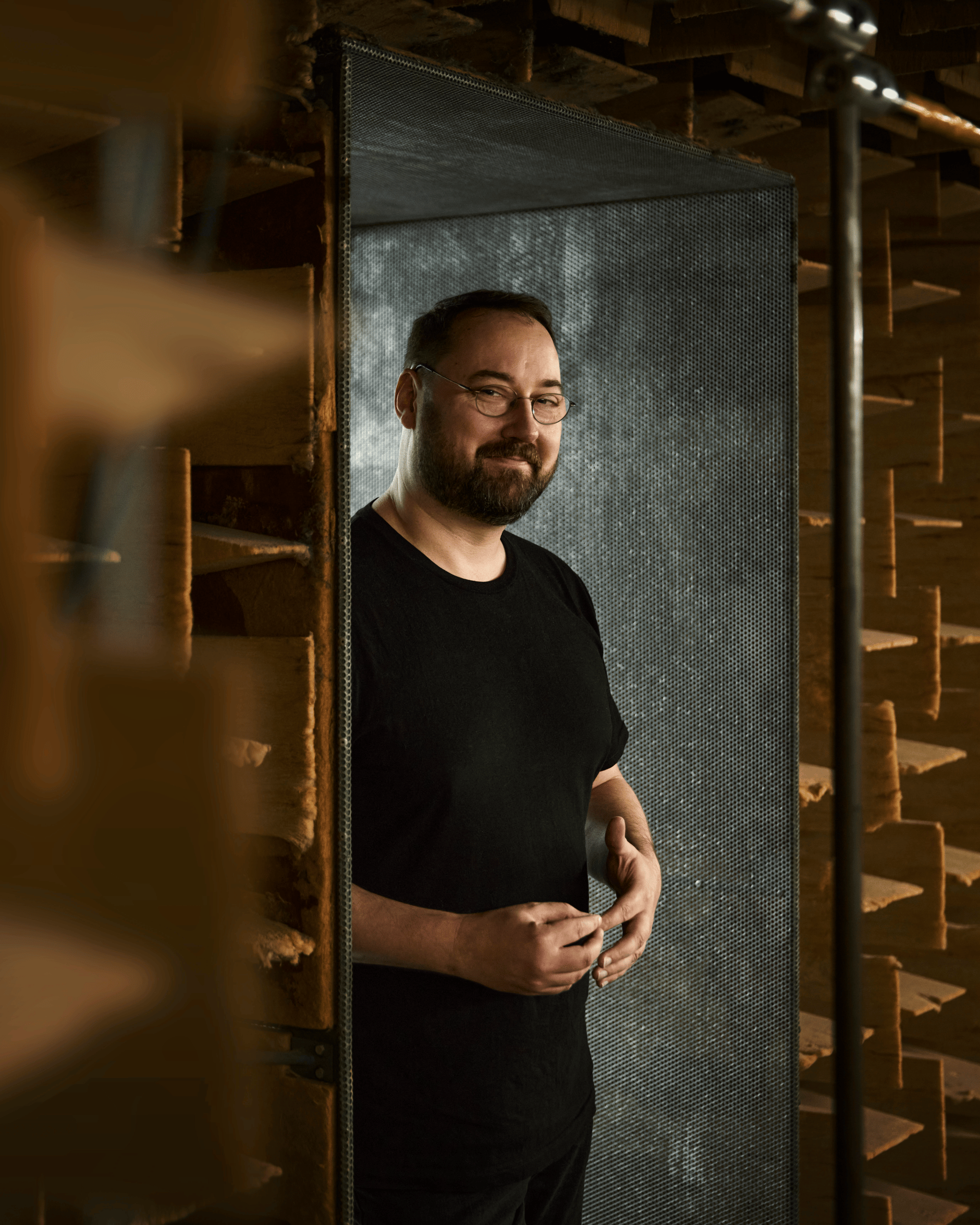 Man standing in anechoic chamber with acoustic foam walls.