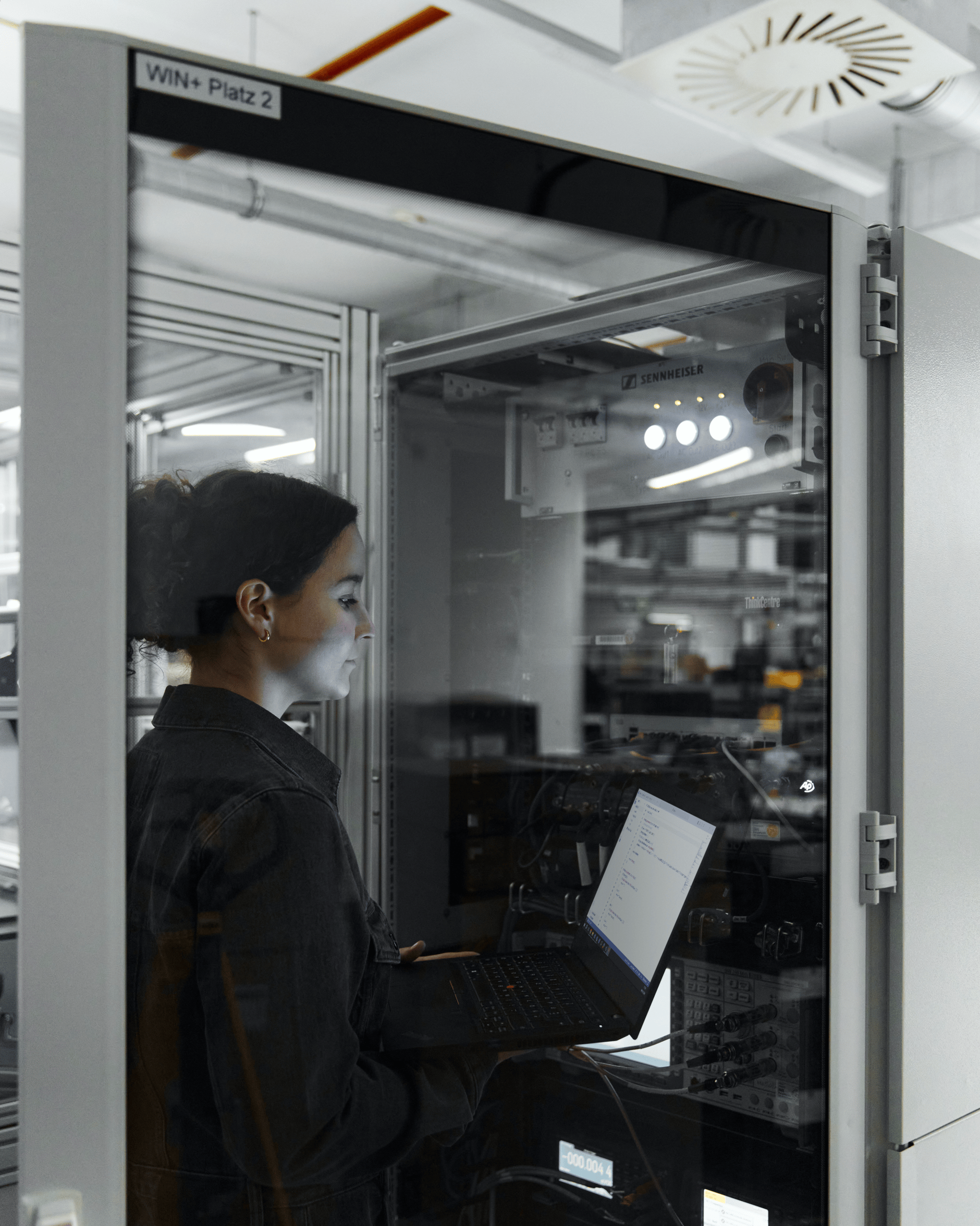 Person working on a laptop inside a server room at Sennheiser facility.