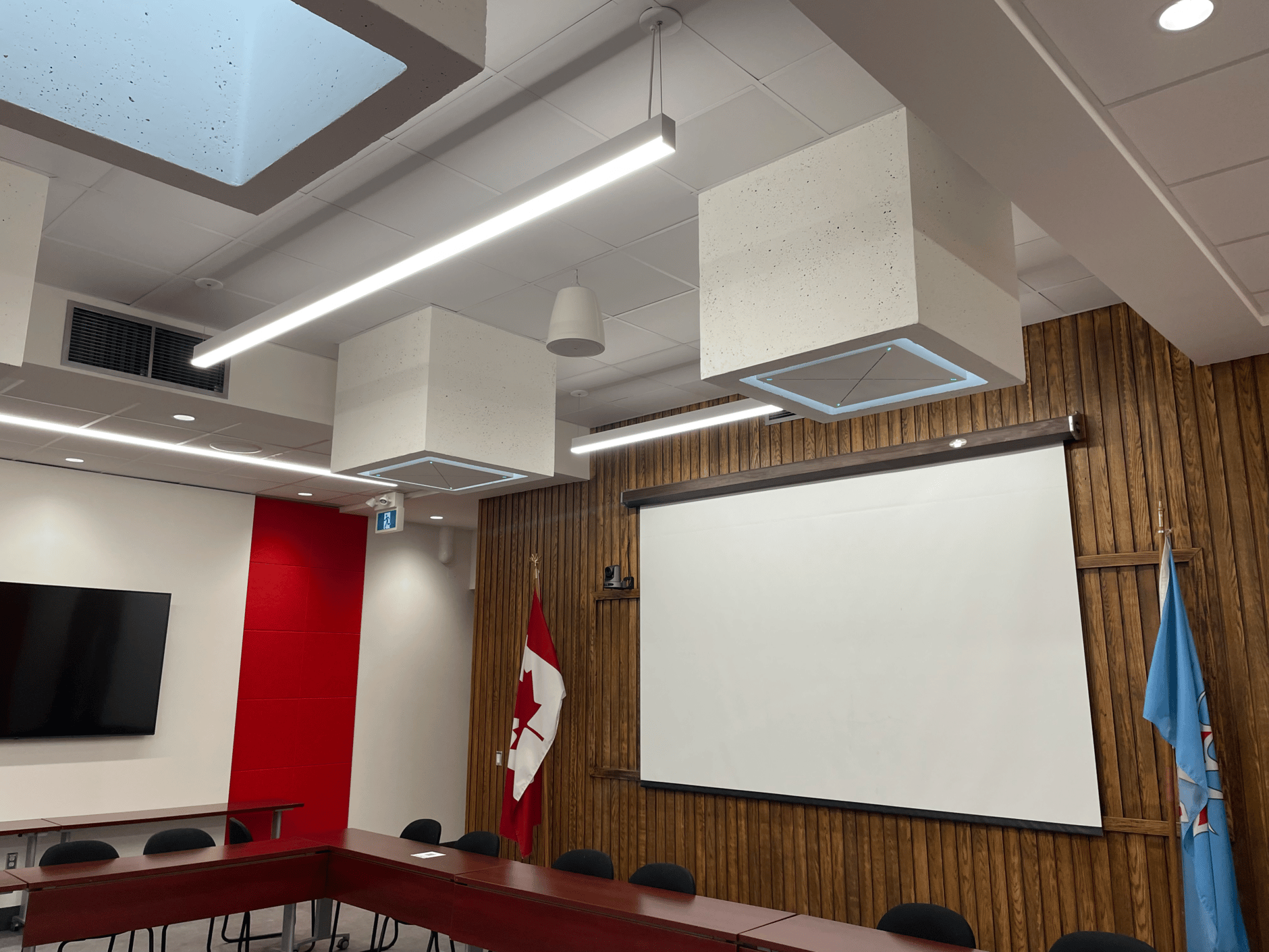 Modern conference room with Canadian flag, projector screen, and wooden paneling.