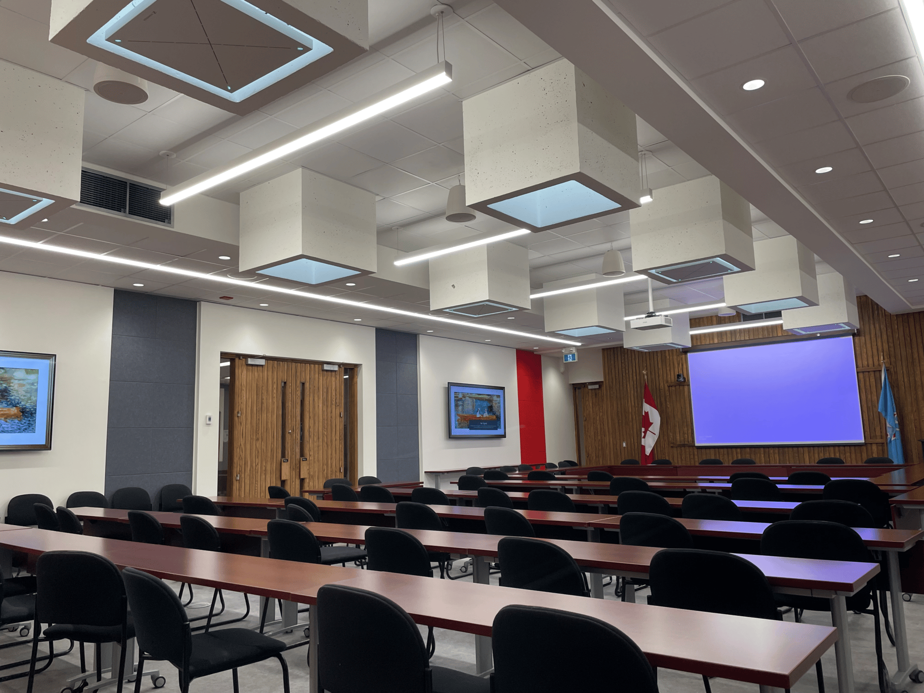 Modern classroom at Carleton University with desks, chairs, and a projector screen.