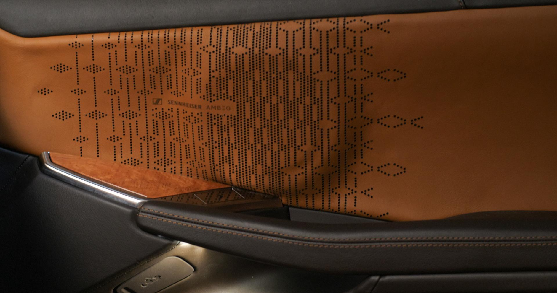 Car Door from the inside with brown leather on which the Sennheiser Ambeo sign is imprinted