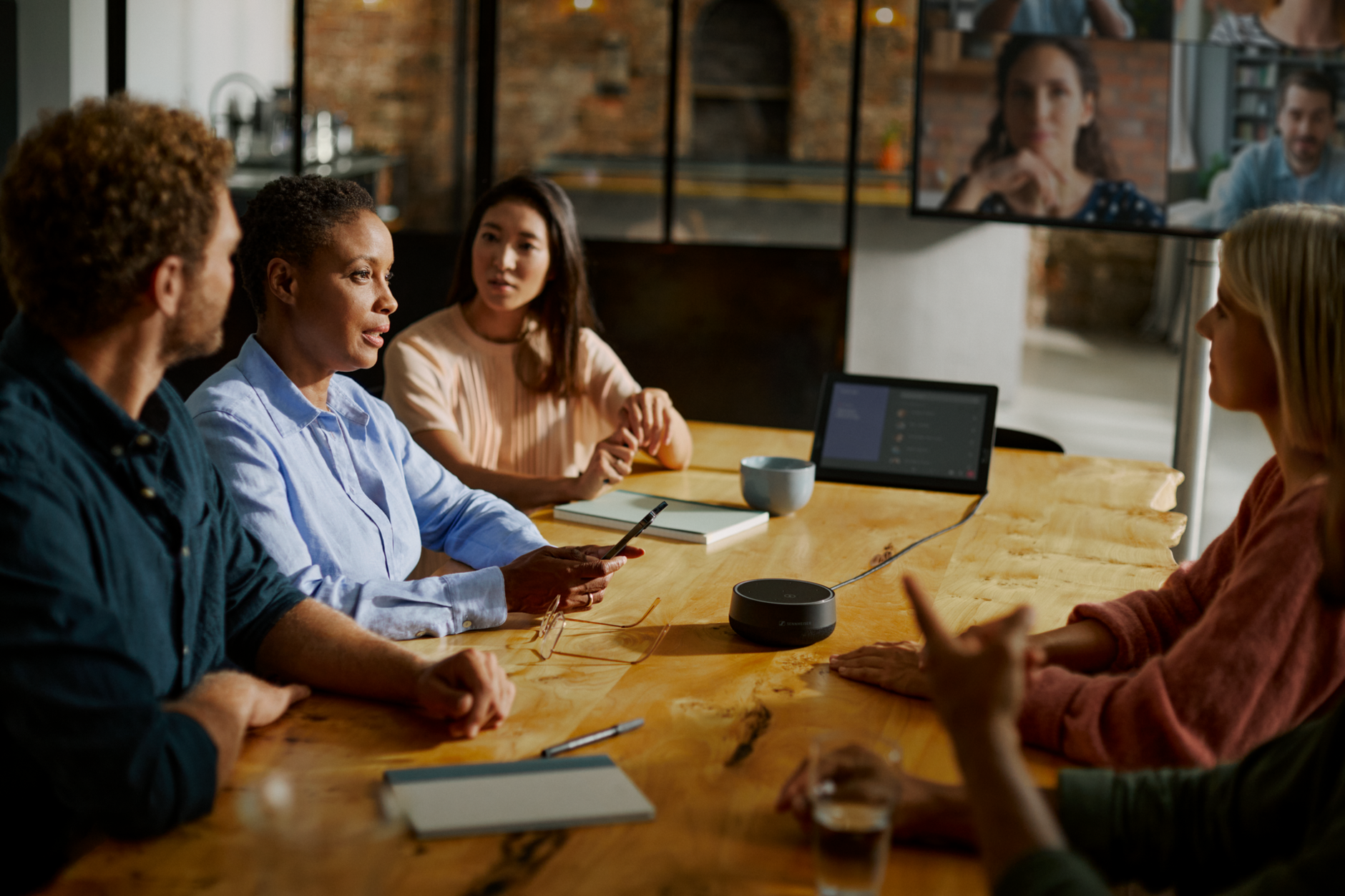 A group of collegues from different nationalities sitting around a table having a meeting with a speaker in the middle
