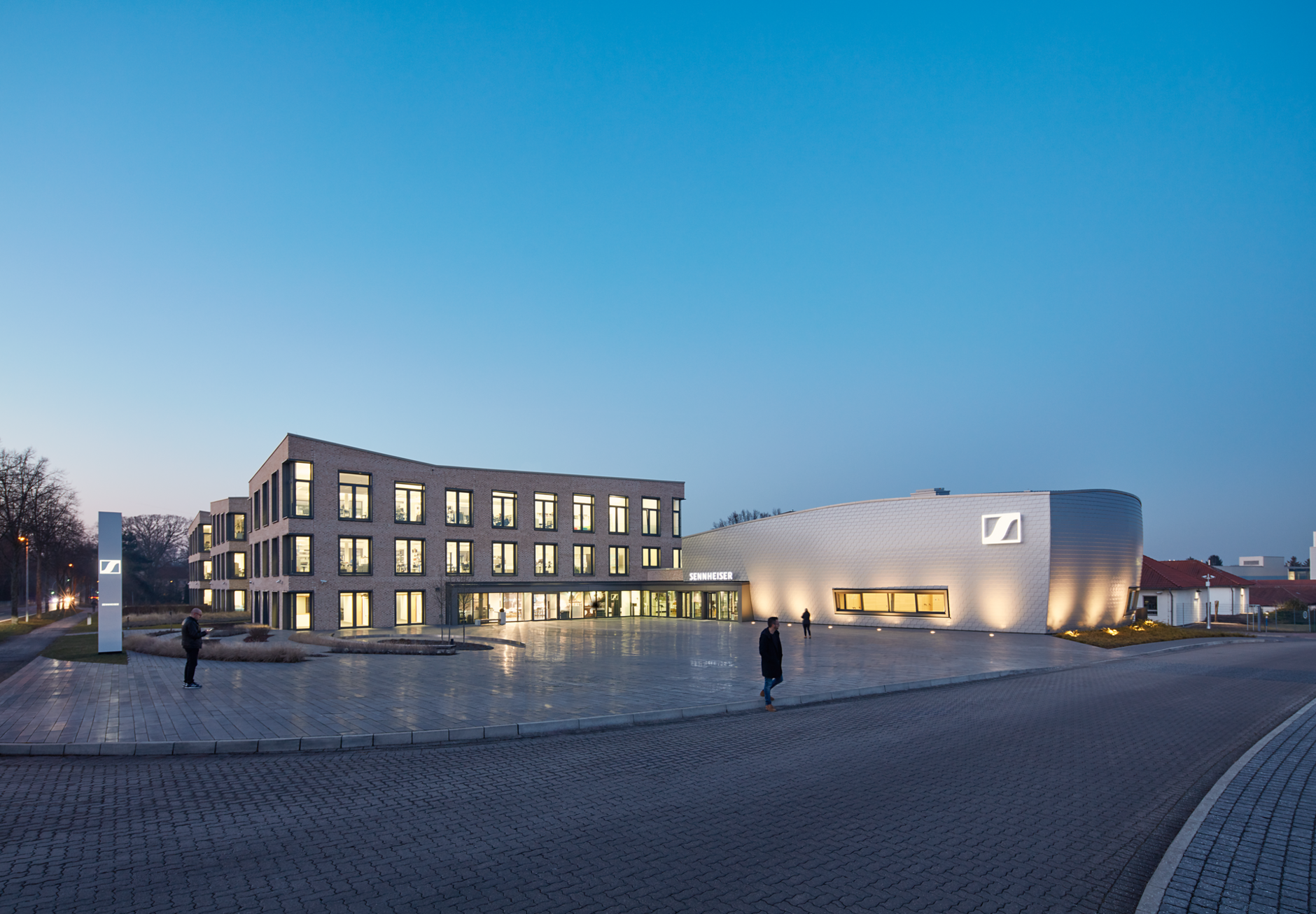 Forecourt and Innovation Campus in Wennebostel during evening hours with brigtly lighted windows.