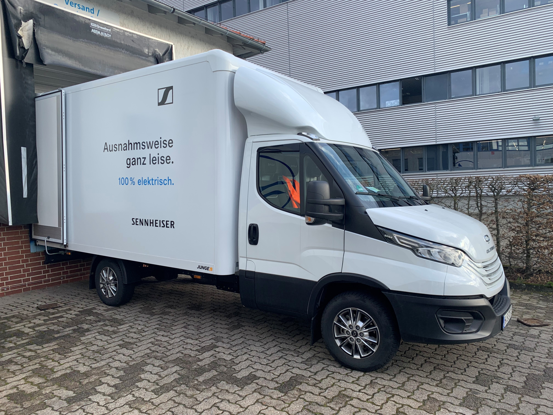 White electronic delivery truck standing in front of Sennheiser´s production hall