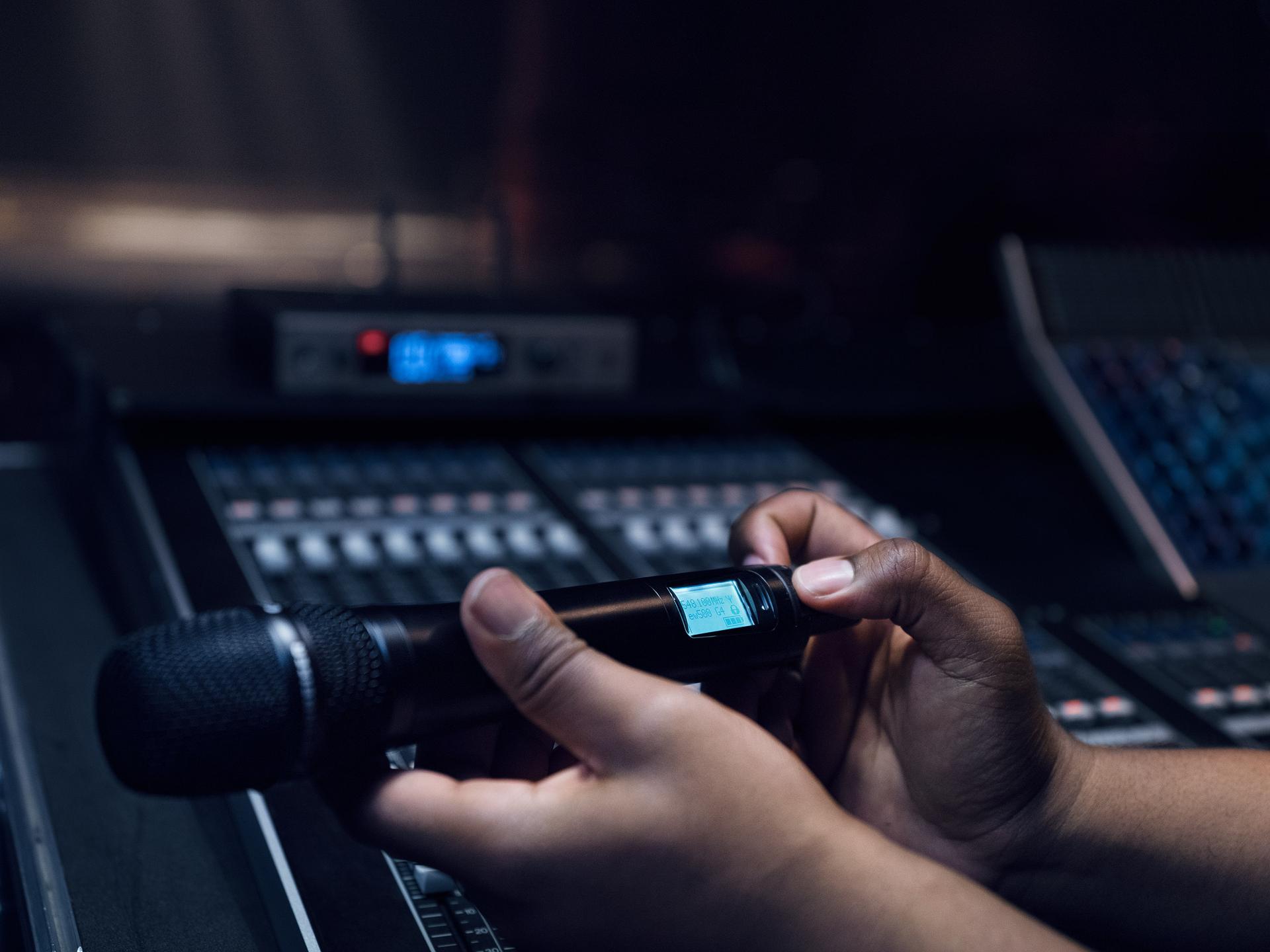 Person holding a Sennheiser G4 UHF wireless microphone in a recording studio.
