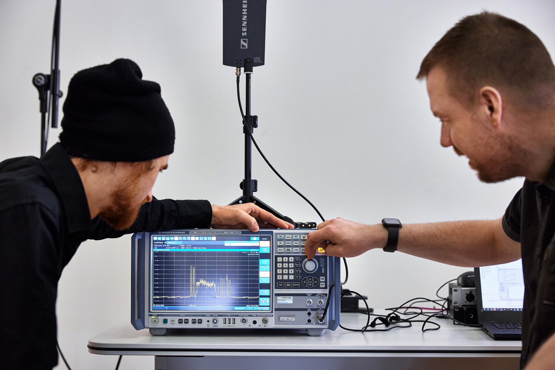 Marco Völzke (l) and Jonas Naesby at the spectrum analyser. The analyser shows four high-power IEM carriers to the left of the broadband WMAS signal, and eight narrowband EW-DX carriers to the right