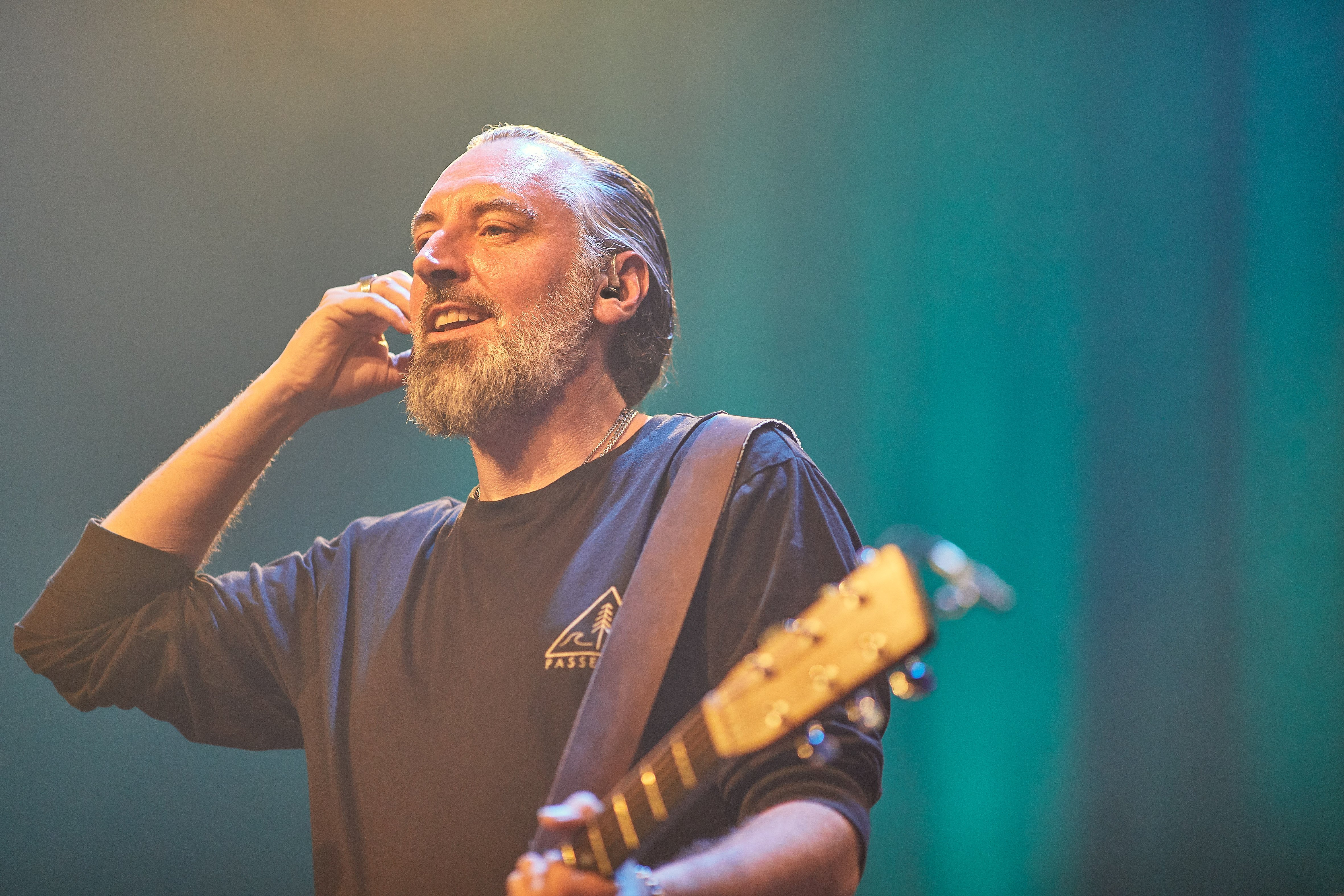 Musician wearing Sennheiser in-ear monitors while performing on stage.