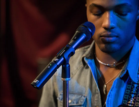 Man singing into a Sennheiser wireless microphone on stage.
