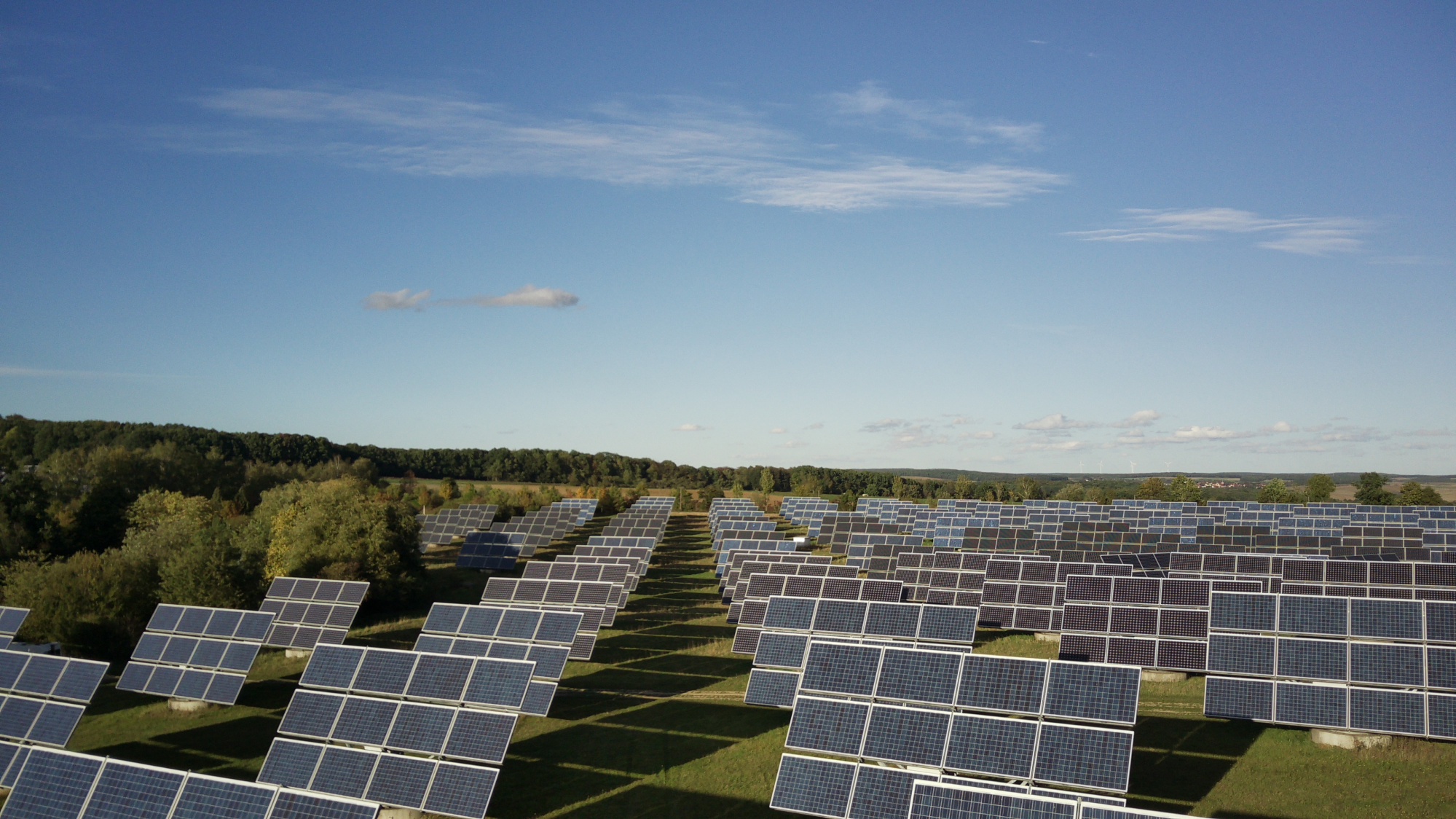 Solar panels in a large field under a clear blue sky.