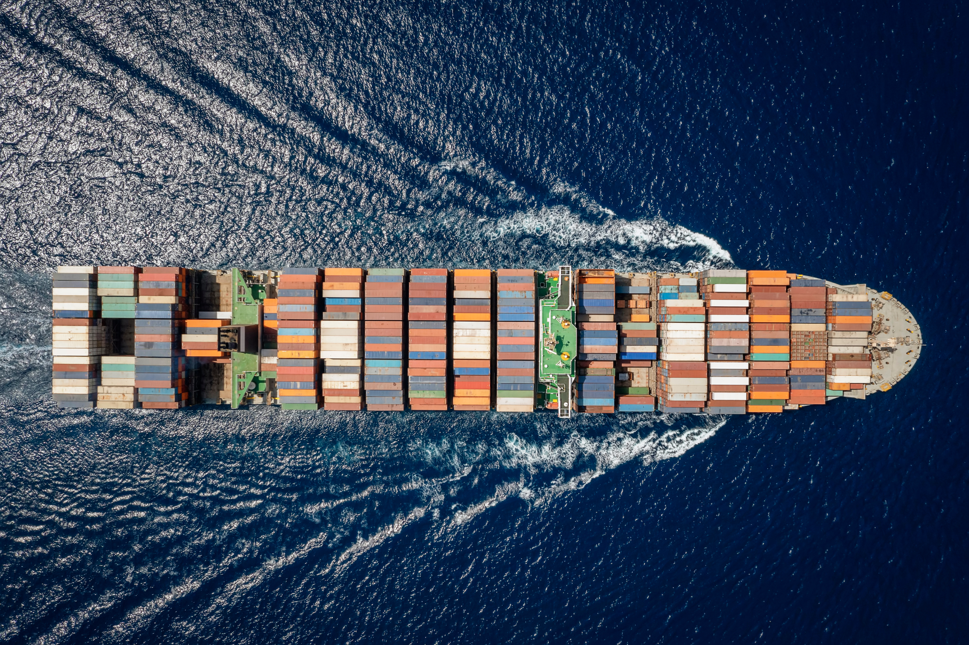 Aerial view of a large cargo ship transporting containers across the ocean.