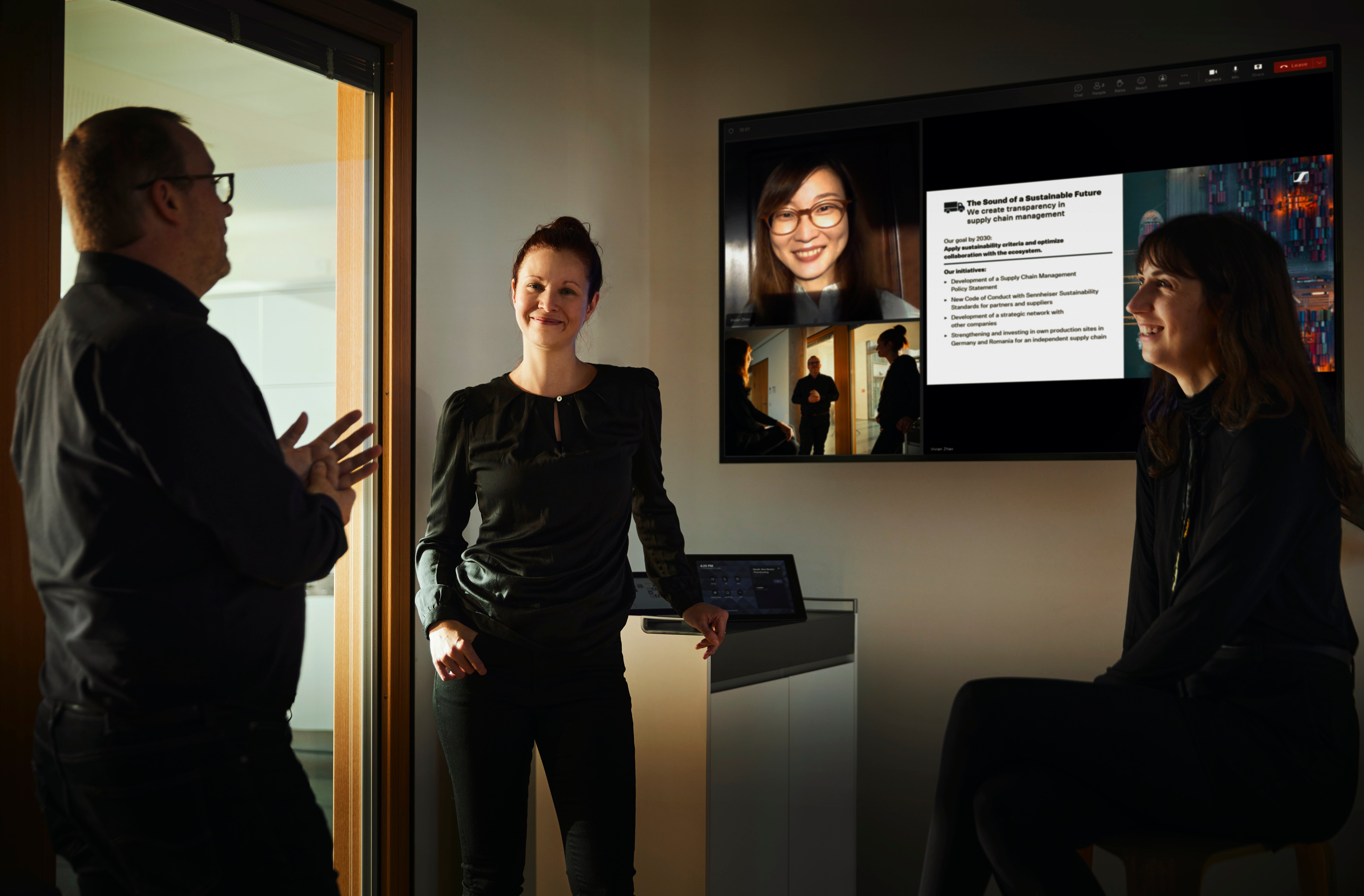 Group of colleagues having a meeting with a video conference screen in an office setting.