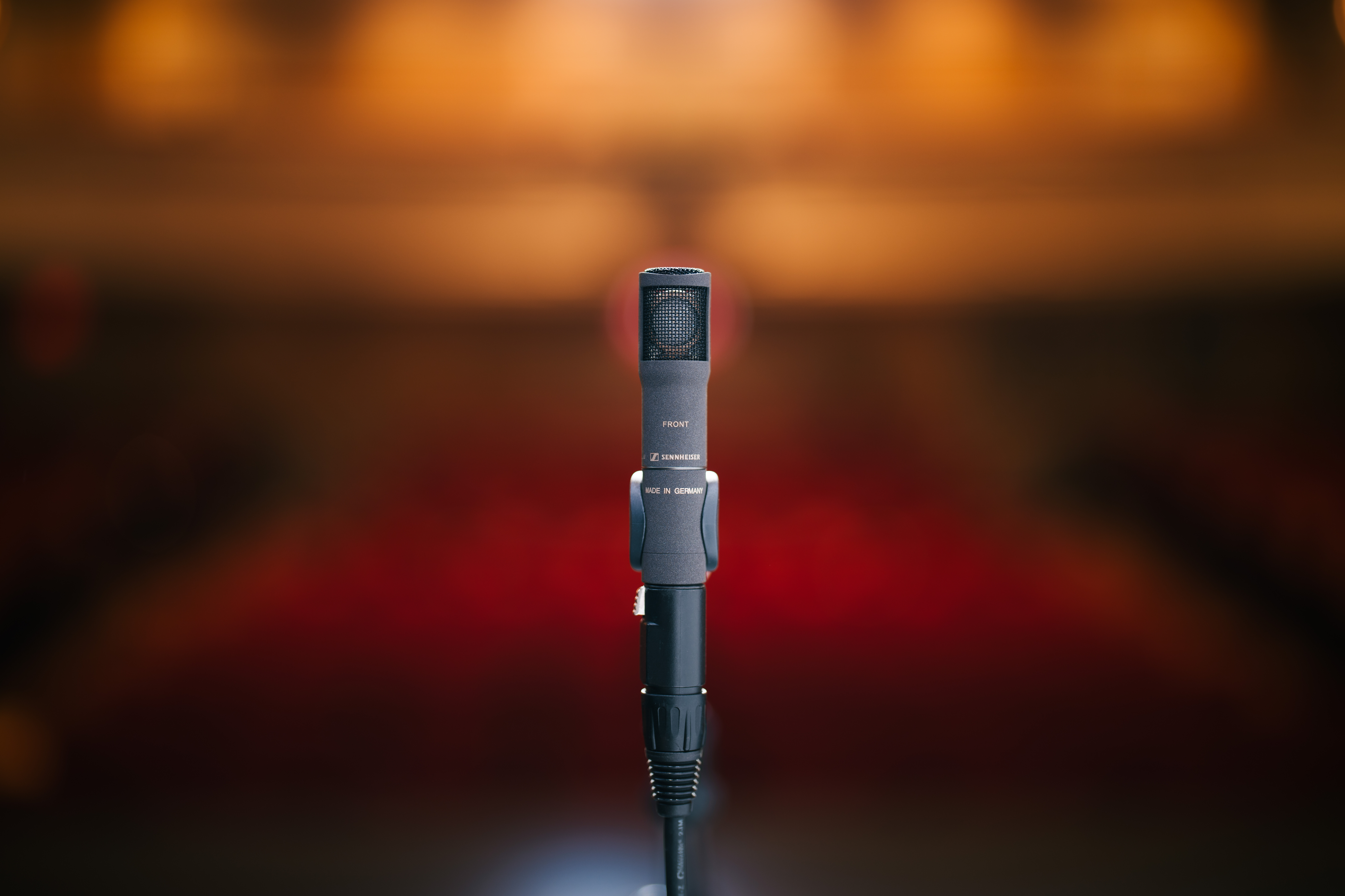 Sennheiser MKH 8030 microphone in use on stage with blurred background.