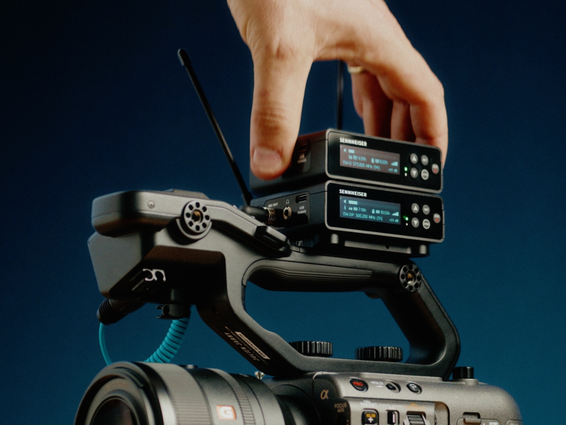 Hand adjusting Sennheiser wireless microphone system on a professional camera.